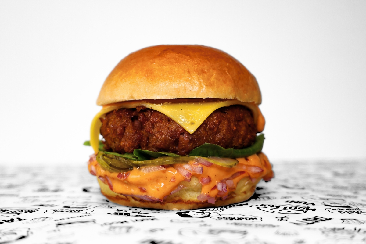 A MooMoo Burger sides bundle featuring golden thick-cut fries, and creamy coleslaw with crispy onions. Presented together on MooMoo Burger’s “Moo! Moo!” illustrated greaseproof paper in Hackney, London. Drinks also includes beers