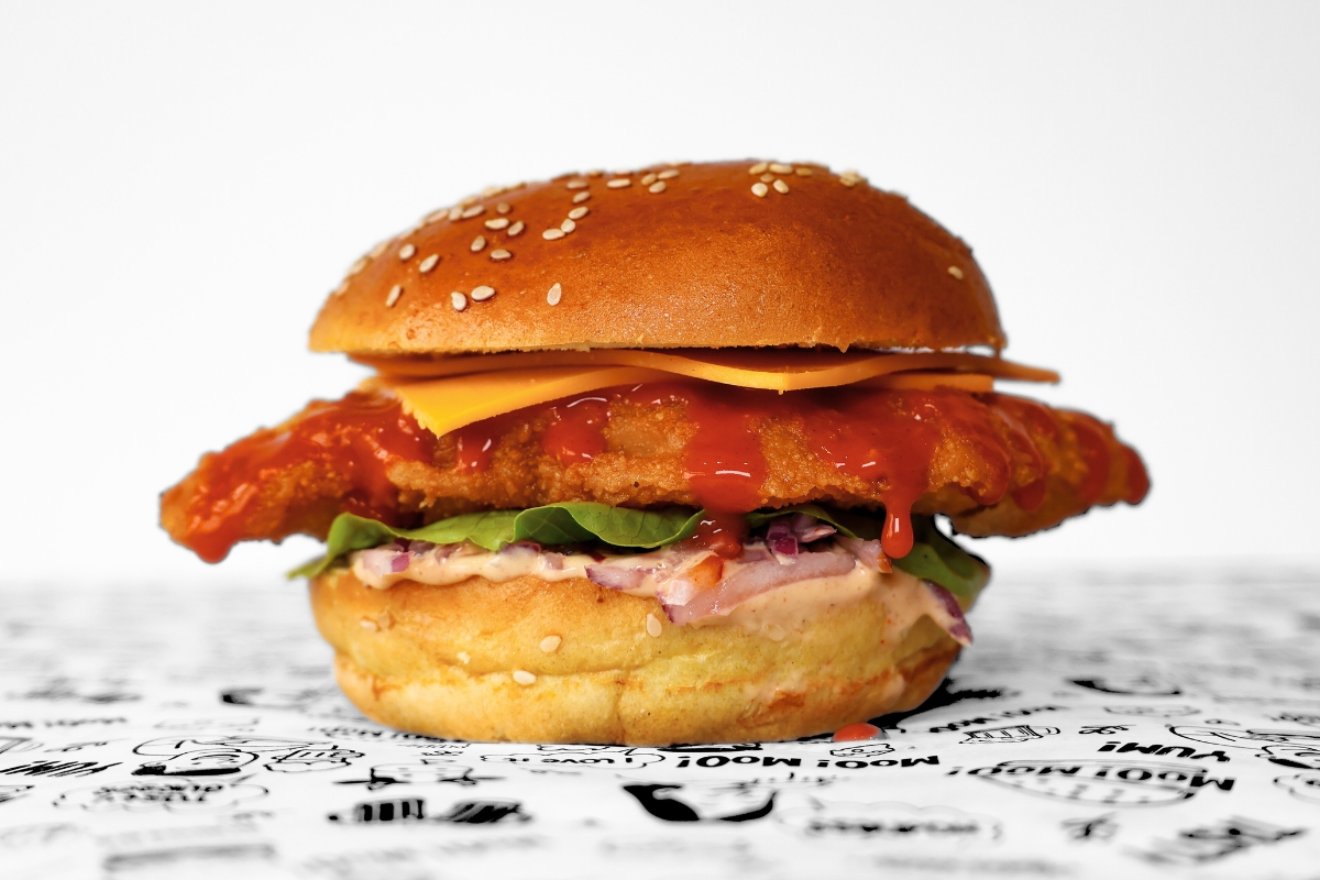 A MooMoo Burger sides bundle featuring golden thick-cut fries, and creamy coleslaw with crispy onions. Presented together on MooMoo Burger’s “Moo! Moo!” illustrated greaseproof paper in Hackney, London. Drinks also includes beers